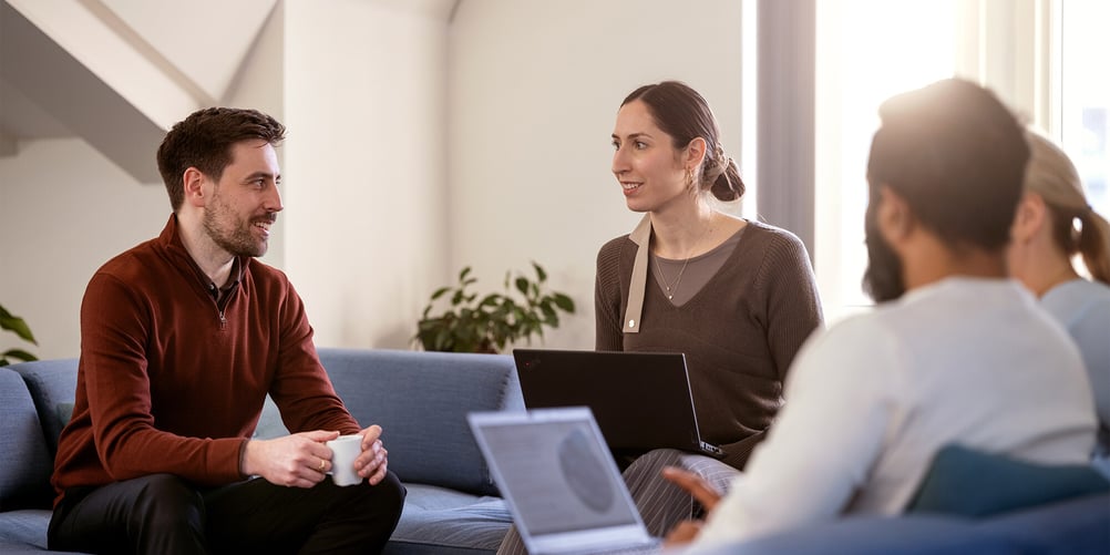 Several colleagues at Admincontrol are sitting on a sofa and discussing together.