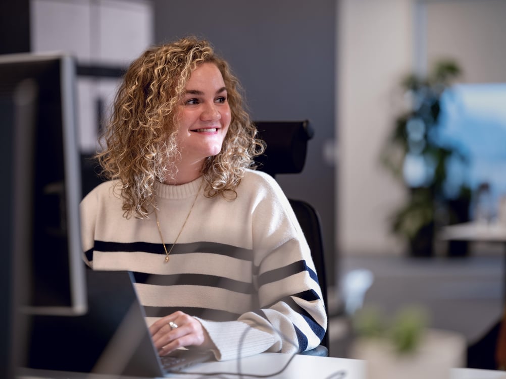 A woman smiles while using her computer.