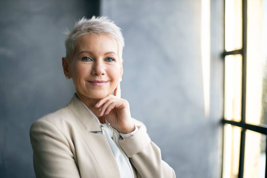 Porträtt av en kvinna med kort vitt hår, klädd i en professionell kostym.