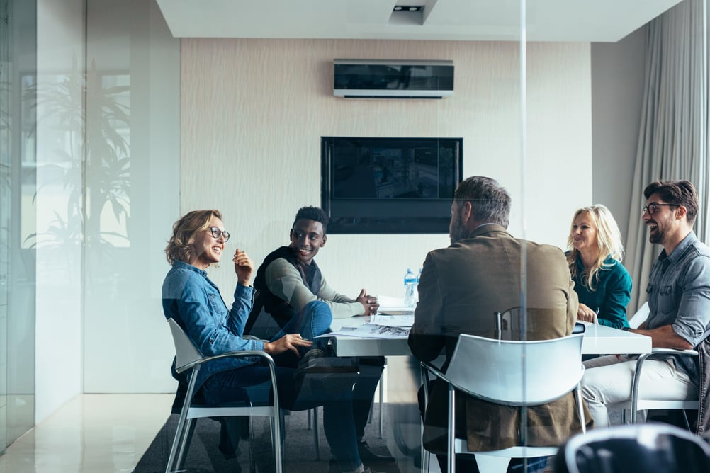 Several employees sitting in a meeting room talking together.
