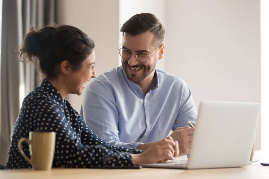 2 colleagues smiling while they coordinate on a project together