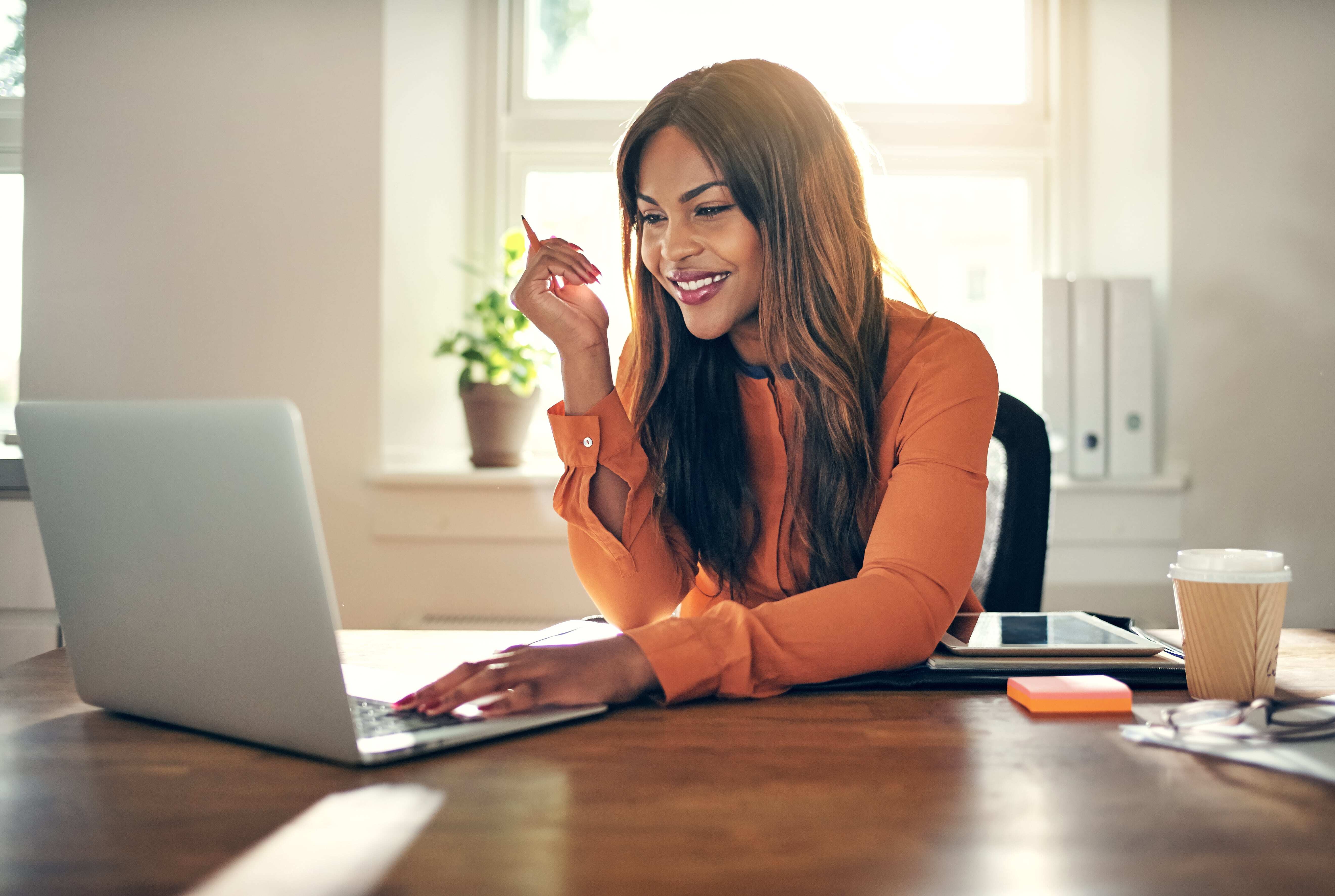 A woman smiling while working on her laptop.