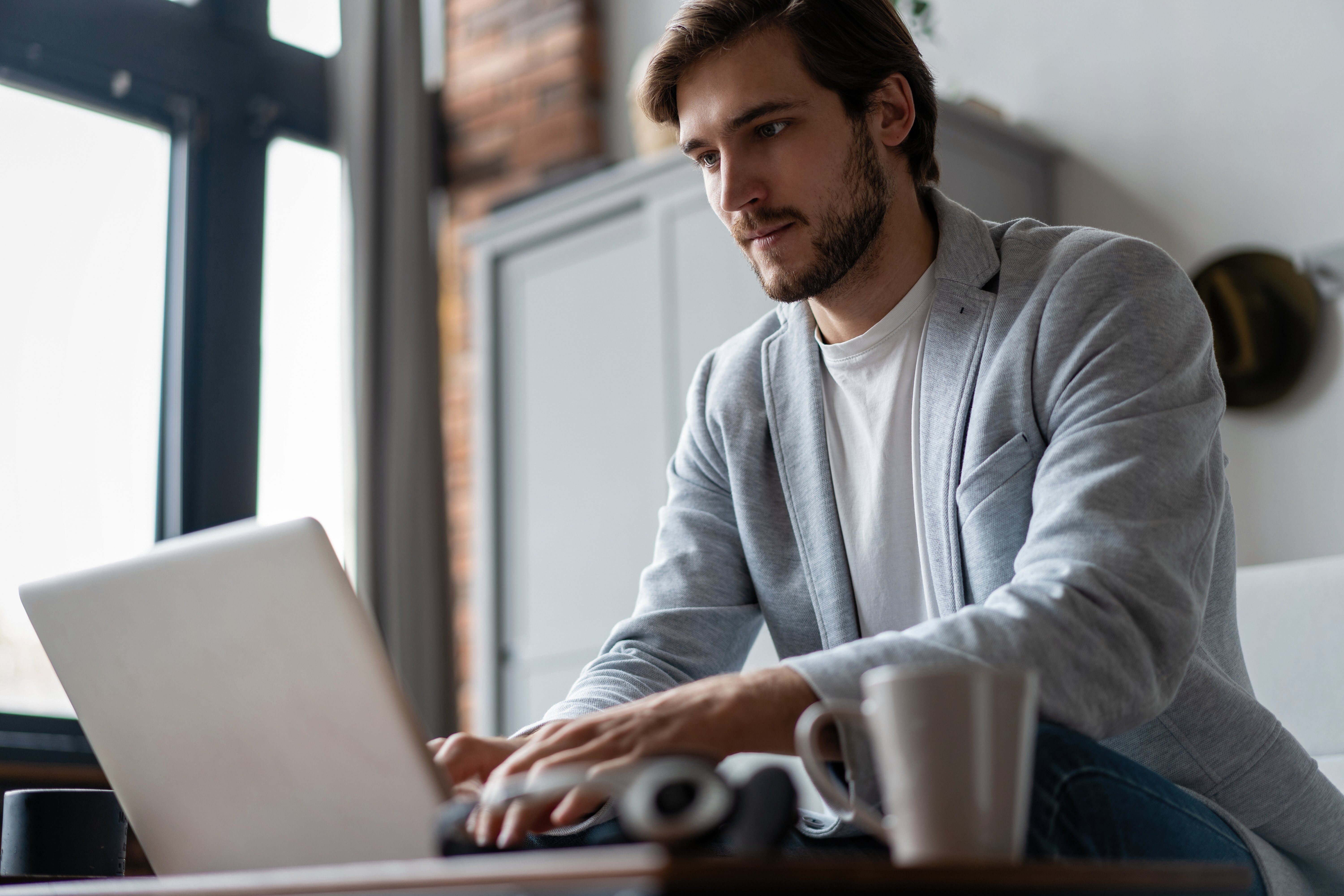 A man is typing on his laptop while seated at a desk.