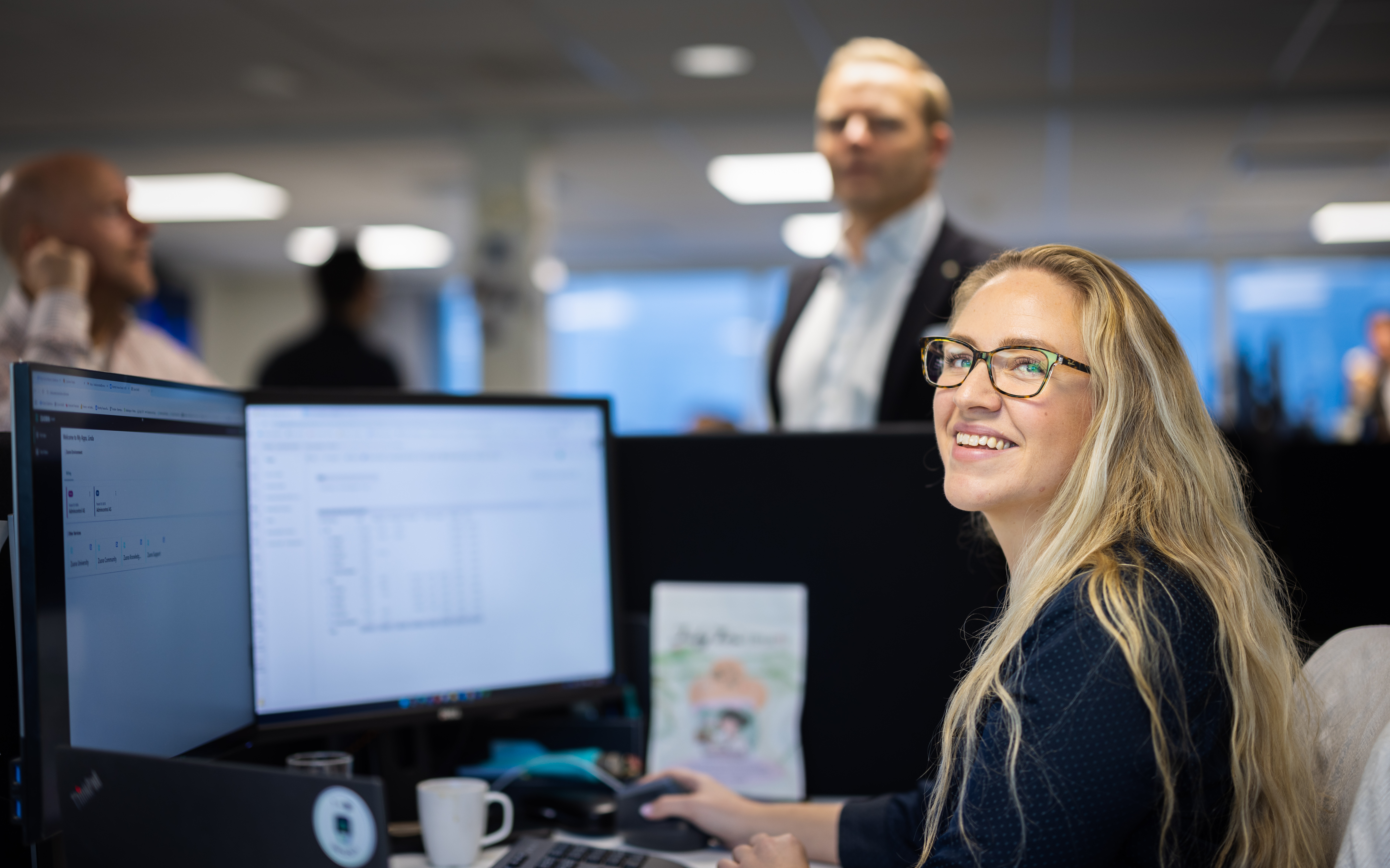 Smiling colleagues gather around a desk. 