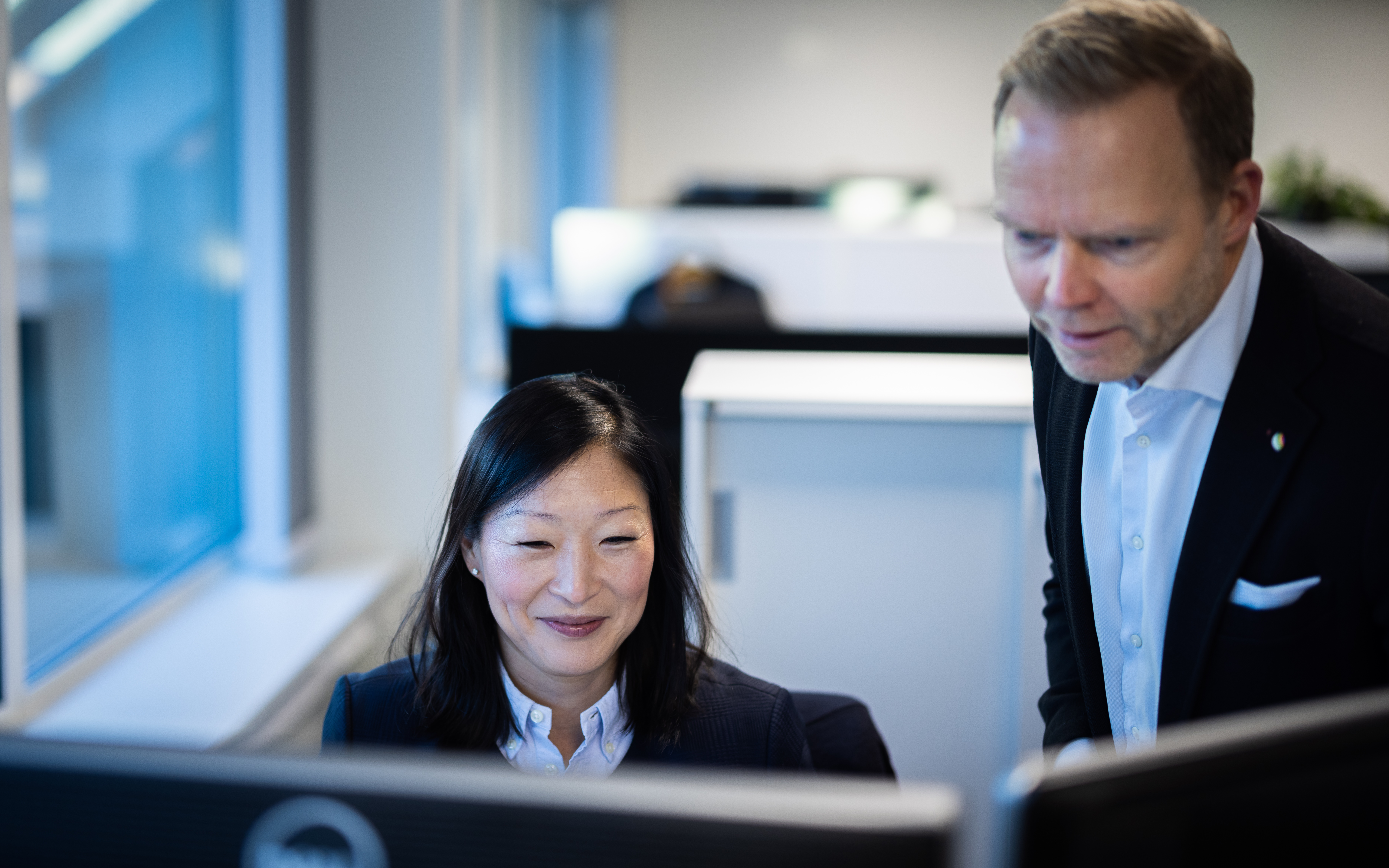 Två kollegor tittar på en datorskärm tillsammans 